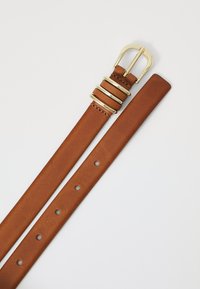 Bruin lederen riem met een goudkleurige metalen gesp en drie decoratieve ringen. Bevat gelijkmatig verdeelde gaten voor maatverstelling. Glad oppervlak.