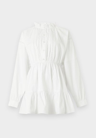 Λευκό πουκάμισο με μακριά μανίκια, βολάν στον ψηλό γιακά, με κουμπιά μπροστά, διακοσμητικό δαντέλα, σούρες στη μέση και φουντωτό στρίφωμα, πάνω σε ανοιχτό φόντο.