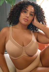 Nude gepaddeerde beha met een gemêleerd netpaneel, verstelbare bandjes en een gladde afwerking. Bijpassende naadloze high-waisted slip.