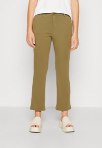 Pantalones verde oliva con un corte ajustado, cintura de media altura y dobladillo acampanado. Hechos de una tela suave y elástica con un cierre de un solo botón.