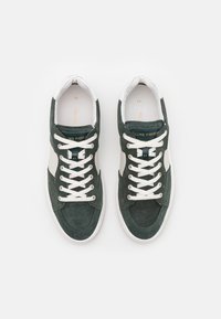 Green suede sneakers with white accents and laces, featuring a rounded toe and textured surface, labeled "Filling Pieces" on the tongue.