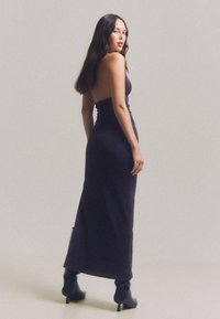 Bordeaux maxi haljina bez naramenica s pripijenim korzetom i lepršavom suknjom. Glatka tekstura s suptilnim sjajem. Nositi s crnim čizmama do koljena.