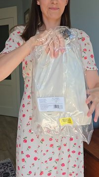 Clear plastic bag containing a white item with a label. The item appears to be a clothing piece, with a string closure at the top.