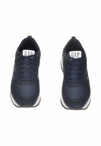 Un paio di sneaker sportive blu navy con suole bianche e lacci neri, viste dall'alto su uno sfondo bianco.