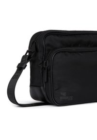 Sort nylon crossbody taske med to lynlåskompartments, justerbar rem og tekstureret logo detalje på forsiden.