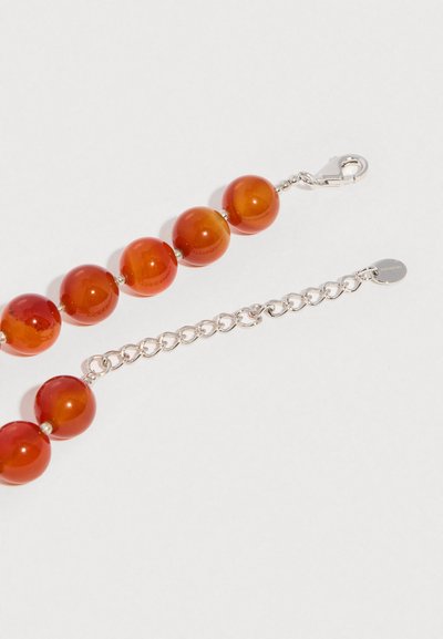 Colier din argint cu mărgele mari, rotunde, lucioase de chihlimbar și închizătoare cu clească de homar pe un fundal alb.