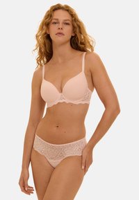 Ensemble de soutien-gorge et culotte rose clair avec détails en dentelle. Le soutien-gorge a des bonnets moulés et des bretelles ajustables ; la culotte présente une large bande de dentelle à la taille.