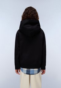 Zwarte hoodie gemaakt van zacht materiaal, met een ontspannen fit en geribbelde manchetten. Daaronder is een blauw-wit geruit shirt zichtbaar.