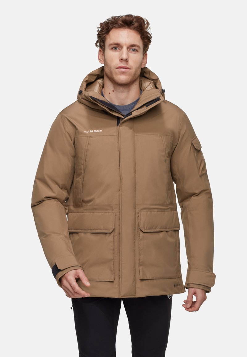 Giacca isolante marrone con cappuccio, dotata di due tasche frontali e chiusura con zip. Tessuto testurizzato con finitura opaca, design leggero.