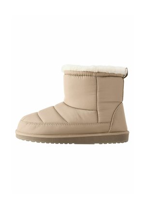 Bottines beige à cheville en matériau synthétique matelassé avec une doublure en fausse fourrure en haut, semelle en caoutchouc texturé et langue à l'arrière.