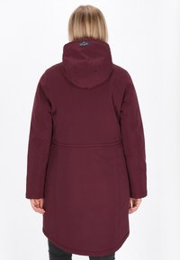 Bordeaux lange jas met capuchon, voorzien van een getailleerde taille, soepele textuur en een afgeronde zoom, ontworpen voor warmte en bedekking.