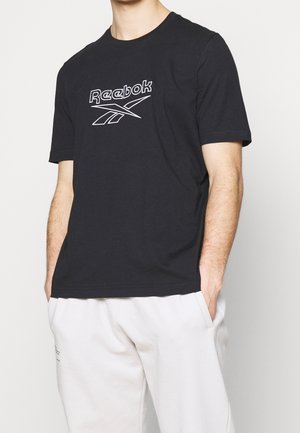 Zwarte katoenen T-shirt met een wit Reebok-logo gecentreerd op de borst. Klassieke ronde halslijn en korte mouwen. Zachte textuur.