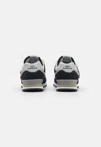 Baskets en suède noir et en mesh avec un talon et des accents gris. Présente le logo "new balance" et une semelle en caoutchouc texturée.