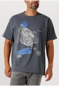 Szara bawełniana koszulka z niebieską okrągłą grafiką i białymi liniami topograficznymi. Krótkie rękawy i luźny krój.