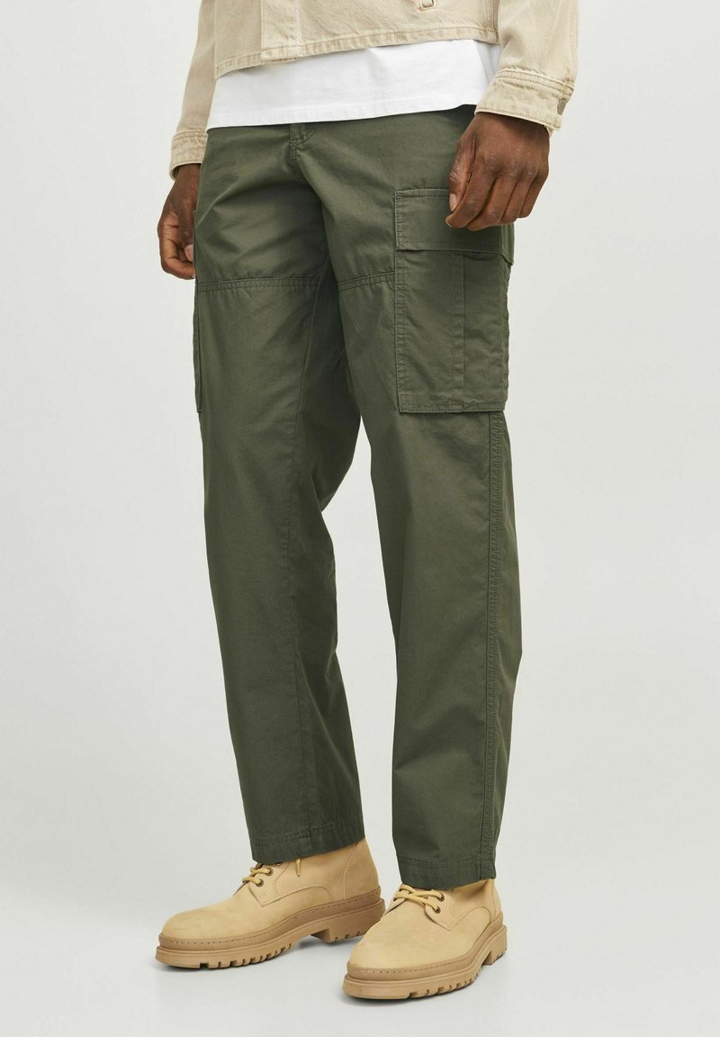 Pantaloni cargo de culoare verde măsliniu, fabricați din bumbac. Au multiple buzunare, croială lejeră și detalii cusute. Se asortează cu pantofi bej cu șireturi.