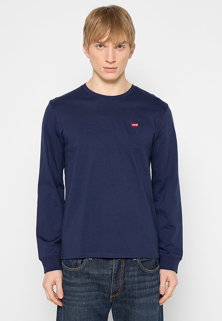 Camiseta de manga larga en color navy hecha de algodón con un escote redondo. Presenta un pequeño logo rojo de Levi's en el pecho. Combinada con jeans oscuros.