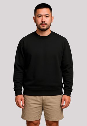Schwarzer Sweatshirt mit Rundhalsausschnitt, gerippten Bündchen und Saum. Getragen mit beigen Shorts, die eine glatte Textur und eine einheitliche Farbe aufweisen.