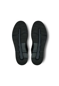 Schwarze Sportschuhsohlen mit strukturiertem Gummigriff, die Zickzack- und Kreis-Muster sowie ein segmentiertes Design für Flexibilität und Traktion aufweisen.