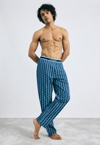Blauwe loungebroek met een patroon van een textuurstof en een elastische tailleband met het Lacoste-logo. Ontworpen met een geometrische print.