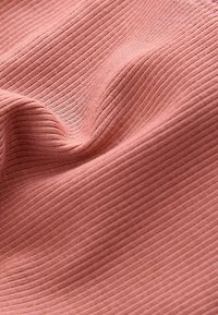 Tissu côtelé dans une douce couleur rose poussière, présentant une surface texturée avec des lignes horizontales régulièrement espacées et un tombé fluide.