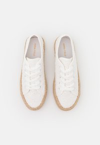 Baskets en toile blanches avec des motifs brodés, bout arrondi, lacets à l'avant et semelle en jute tressé. L'intérieur présente une marquage en or.