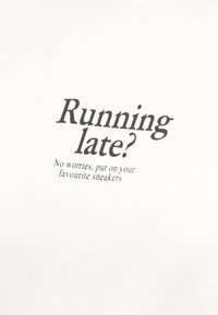 Το κείμενο σε λευκό ύφασμα λέει: «Καθυστερείς; Μην ανησυχείς, φόρεσε τα αγαπημένα σου αθλητικά παπούτσια.»