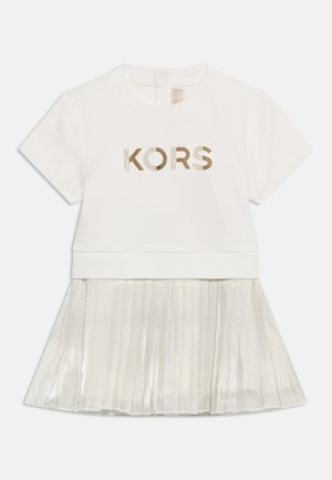 Balta kleita ar īsām piedurknēm un zelta uzrakstu "KORS" augšpusē, ar pie pleciem piestiprinātu kroku, spīdīgu svārku.