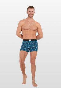 Boxer-briefs pour hommes en tissu bleu arborant un motif géométrique coloré. Ceinture élastique noire avec une petite étiquette logo.