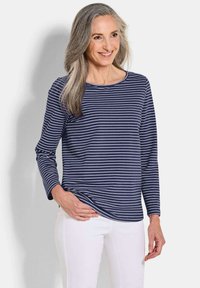 Navy gestreiftes Langarmshirt mit rundem Ausschnitt, aus weichem Stoff, kombiniert mit weißen Hosen.