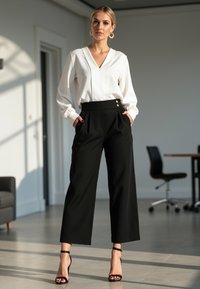Biała bluzka z dekoltem w serek i długimi rękawami, zestawiona z czarnymi spodniami o wysokim stanie z przodu z fałdami i guzikami. Czarne sandały na obcasie.