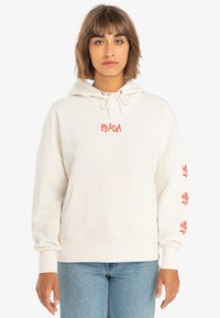 Cream-colored hoodie made from soft material. Features a front pocket, drawstring hood, and red rose prints on the sleeves.