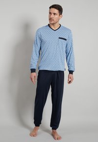 Blue striped long-sleeve V-neck top with a black pocket, paired with navy drawstring trousers. Soft fabric, relaxed fit, and ribbed cuffs.