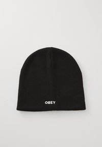 Črna pletena kapa z tesnim prileganjem, na sprednji strani pa je bela vezenina z besedilom "OBEY". Gladka tekstura z preprostim, minimalističnim dizajnom.