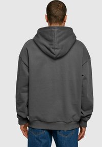 Sudadera oversized de color gris oscuro con capucha con cordón, puños y dobladillo acanalados, textura suave y detalles de costura mínimos en la parte posterior.