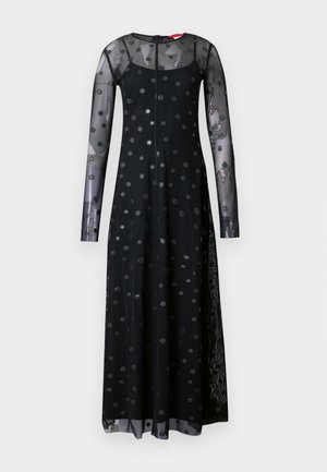 Long black dress with long sheer sleeves, featuring a polka dot pattern. Fabric is lightweight, with a flowing silhouette and round neckline.