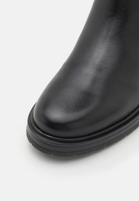Schwarze Leder Stiefelette mit runder Zehenform, glatter Textur und dicker Gummisohle. Verfügt über ein schlankes, minimalistisches Design.