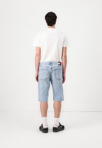 Light blue denim shorts with a relaxed fit, raw hem, and five-pocket design. White t-shirt, black shoes, and white socks complete the look.