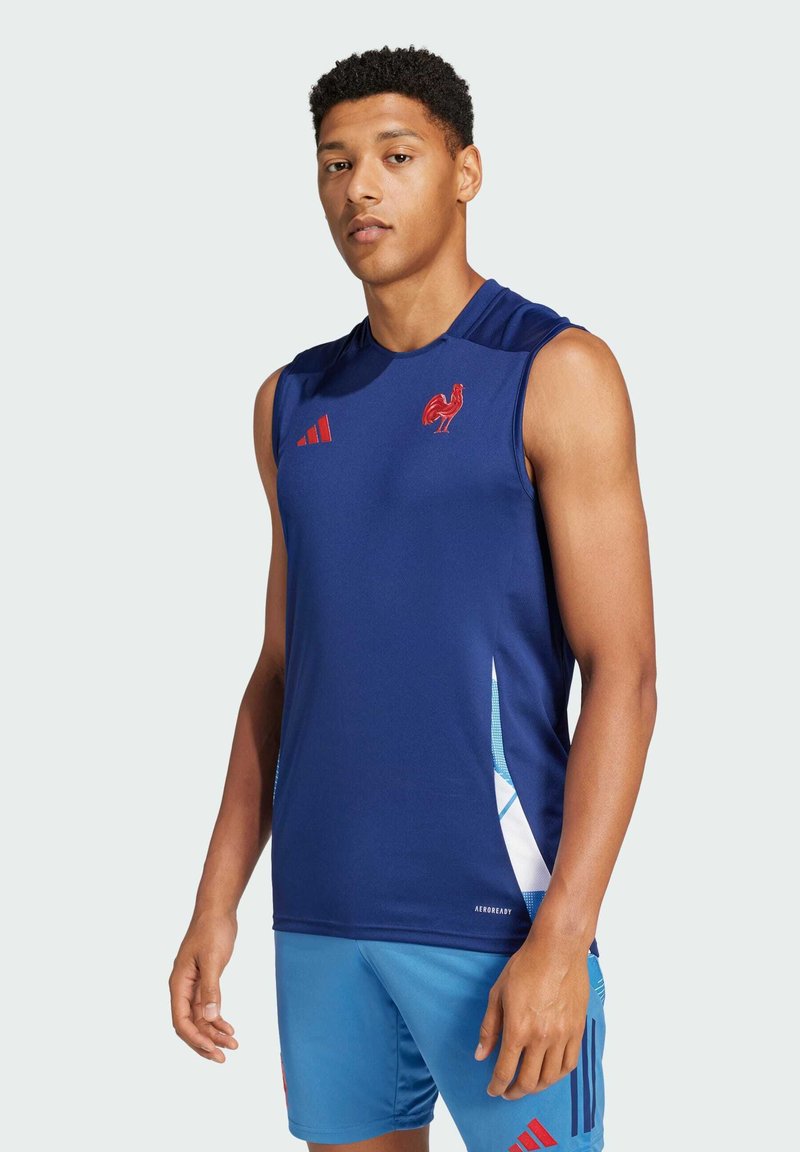 Top deportivo sin mangas azul marino con un emblema de gallo rojo y tres franjas rojas, fabricado en un material transpirable con una textura suave.