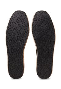 Suole di scarpe in gomma nera con un motivo texturizzato che presenta cerchi interconnessi, bordate da un materiale di colore chiaro.