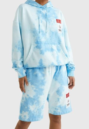 Zestaw składający się z jasnoniebieskiej i białej bluzy z kapturem z efektem tie-dye oraz szortów, z przednimi kieszeniami i czerwono-białymi naszywkami Tommy Jeans na piersi i udzie.
