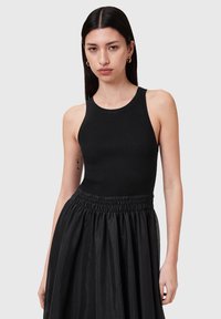 Svart ribbad linne med rund halsringning, tillsammans med en svart, flödig, samlad kjol. Slät textur; minimalistisk design utan mönster.