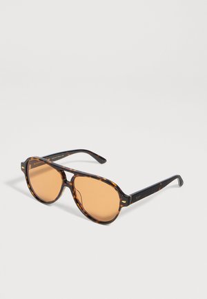 Lunettes de soleil à monture écaille de tortue et verres ronds teintés d’ambre, présentées ouvertes sur un fond clair.