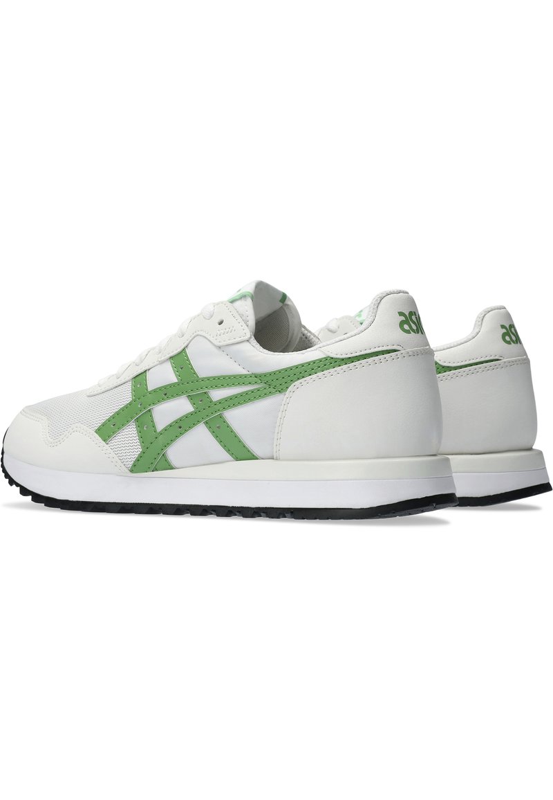 Zapatillas blancas con detalles en verde, materiales de malla y cuero, puntera redondeada, superficies texturizadas y una suela de goma negra para mayor tracción.