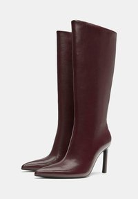 Cizme înalte până la genunchi din piele vișinie, cu un design elegant, vârf ascuțit și toc stiletto, având o textură netedă și lucioasă.