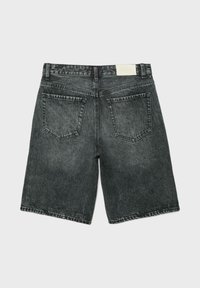 Short en denim noir délavé à l'acide avec deux poches arrière, passants de ceinture et une étiquette blanche sur la ceinture, vu de dos.