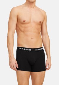 Schwarze Boxer-Briefs aus Baumwolle mit einem breiten elastischen Bund, der mit dem weißen Branding "JACK & JONES" versehen ist. Enganliegendes Design, glatte Textur.