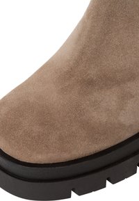 Stivaletto in camoscio color marrone chiaro con una texture liscia, punta rotonda e suola spessa in gomma nera con dettagli scanalati per una migliore aderenza.