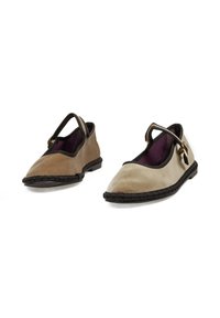 Zapatos bicolor marrones y grises con suela plana, punta redondeada, correa lateral y detalle trenzado a lo largo del borde. Textura suave y aterciopelada.