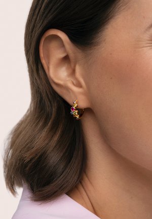 Pendiente de aro de oro con piedras preciosas de colores, con acentos en rosa, púrpura y verde. Vista en primer plano que enfatiza el diseño y la textura.