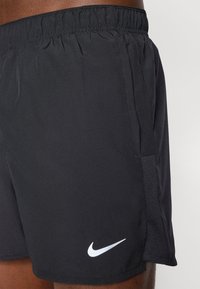 Mustat urheilushortsit, jotka on valmistettu kevyestä kankaasta. Niissä on joustava vyötärönauha, sivutaskut ja valkoinen Nike Swoosh -logo.